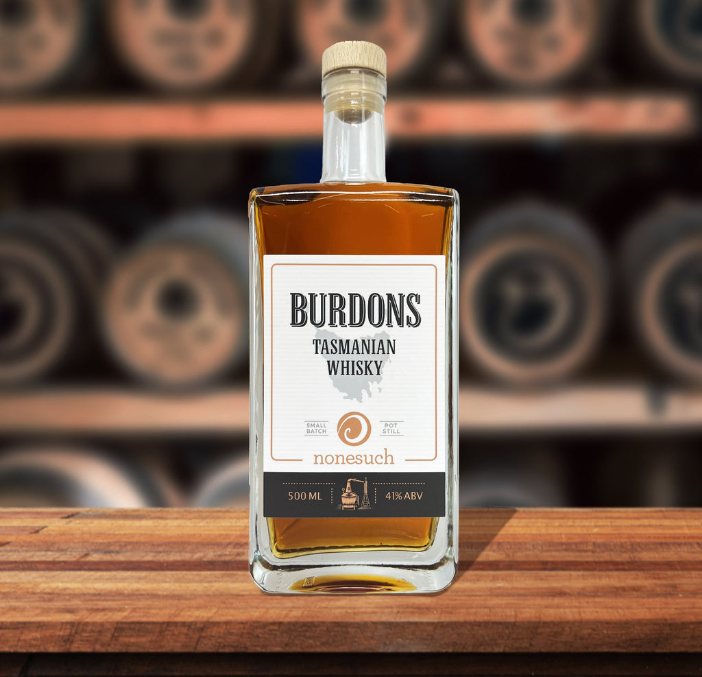 Burdons tasmanian whisky on a wood table with whisky barrels in the background